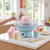 Blue candy floss machine on kitchen counter with pink candy floss in pastel cups