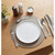Table setting with white plate, silver cutlery, and neutral placemat on wooden table