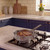Silver frying pan with cooked steak on gas hob in modern kitchen