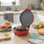 Red electric burger grill with cooked patty, prep ingredients visible in a kitchen setting