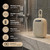 Cream waterproof portable speaker with carry loop shown on bathroom shelf