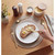 Gold cutlery set with butter spreader and sourdough bread on white plate, breakfast setting