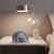 Foldable blue wireless headphones on bedside table with lamp and white orchid vase
