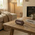 Portable brown wireless speaker on rustic wooden table in cosy living room setting