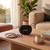 Black portable Bluetooth speaker on wooden coffee table in cosy living room