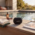 Black portable Bluetooth speaker on poolside table, outdoor setting
