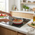 Cream frying pan with gold handle cooking tomato sauce on modern induction hob