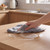 Hand wiping wooden worktop with grey cloth
