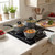 Set of three grey non-stick saucepans with glass lids on a hob in a modern kitchen