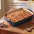 Rectangular blue enamel cast iron baking dish filled with crumble, shown on wooden table.