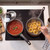 Cooking hob with two pans, one has tomato sauce, the other boiling pasta nests