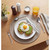 Avocado toast with fried egg on plate, breakfast setting with cutlery and orange juice