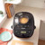 Black bread maker with viewing window kneading dough on kitchen worktop