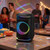 Black wireless party speaker with LED lights on table at indoor gathering