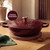 Red cast iron casserole dish with lid and gold handle, shown with Lifetime Guarantee badge.