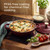 Deep red casserole dish with spinach and cheese bake, shown on induction hob