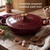Red enamel cast iron casserole dish with lid and gold knob on wooden kitchen table