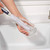 Bottle brush cleaning clear glass vase at kitchen sink