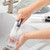 Glass cleaning brush with blue handle used to wash tall glass in kitchen sink