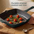 Green enamel square cast iron grill pan with tomatoes and herbs, shown on a wooden board