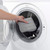 Hand placing grey cleaning pad into washing machine