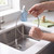 Flexible silver sink drain cleaning brush held over kitchen sink