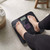 Black digital bathroom scale in use, showing weight reading on display