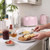 Pink toaster and kettle on kitchen counter, morning breakfast scene with toast, butter, and spreads