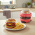 Red mini burger maker with burger patty beside plated burger and chips