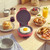 Red mini breakfast maker with fried egg on grill plate
