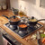 Set of three black saucepans with glass lids cooking vegetables on gas hob in kitchen