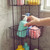 Black shower caddy with bottles, sponges and bath puff in shower corner