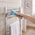 Hand using teal microfibre brush to clean chrome heated towel rail