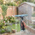 Handheld window vacuum cleaning glass with soapy water, garden view in background