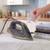 Steam iron being filled with water beside folded shirts