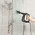 Handheld steam cleaner removing grout stains from tiled wall