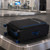 Black medium suitcase with blue trim on an airport baggage carousel
