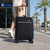 Black cabin suitcase with blue trim and four wheels, shown being pulled outdoors