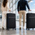 Two travellers with black spinner suitcases in an airport terminal