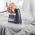 Hand ironing a light grey shirt with a silver steam iron