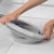 Grey collapsible washing-up bowl being folded, shown on tiled floor.