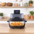 Grey digital air fryer with glass bowl cooking chips on kitchen worktop