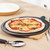 Homemade margherita pizza with basil on black pizza tray, shown on kitchen counter