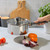 Stainless steel saucepan with lid held over ingredients on kitchen counter