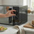 Person adjusting black microwave dials on kitchen counter, loaf and avocado toast in view