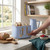 Blue four-slice toaster with bread, wooden controls, used in modern kitchen setting