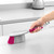 Hand using pink and grey cleaning brush on kitchen worktop