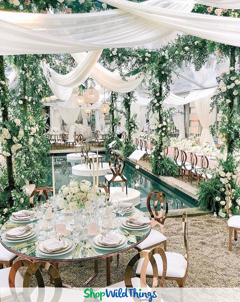 Greenery hanging in the tent at Green Acres with chandeliers and tall  flower centerpieces - Floral V Designs