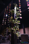 Colorful artificial flower garlands hanging from ceiling at event venue with floral greenery installation and dramatic lighting – ShopWildThings.com
