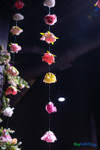 Colorful artificial flower garlands hanging from ceiling at event venue with floral greenery installation and dramatic lighting – ShopWildThings.com